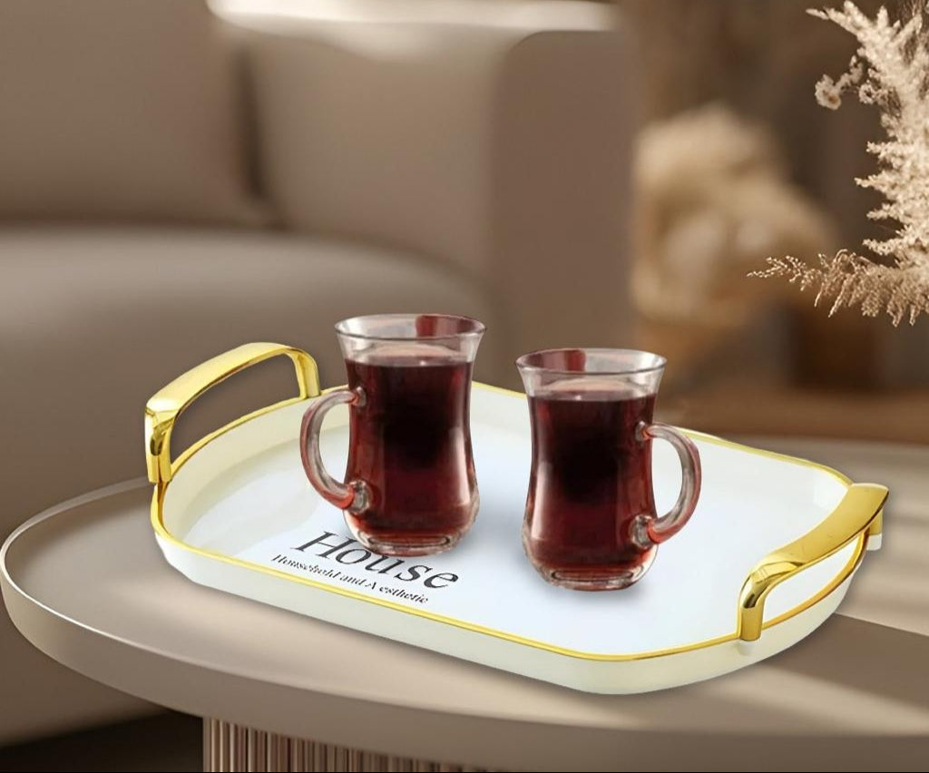 Two glasses of red liquid on a decorative tray with 'House' branding in a cozy living room setting.